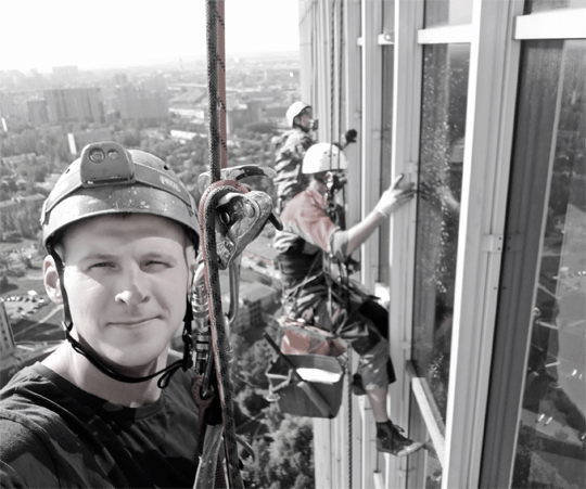 Команда промышленных альпинистов на фасаде очень высокого здания
