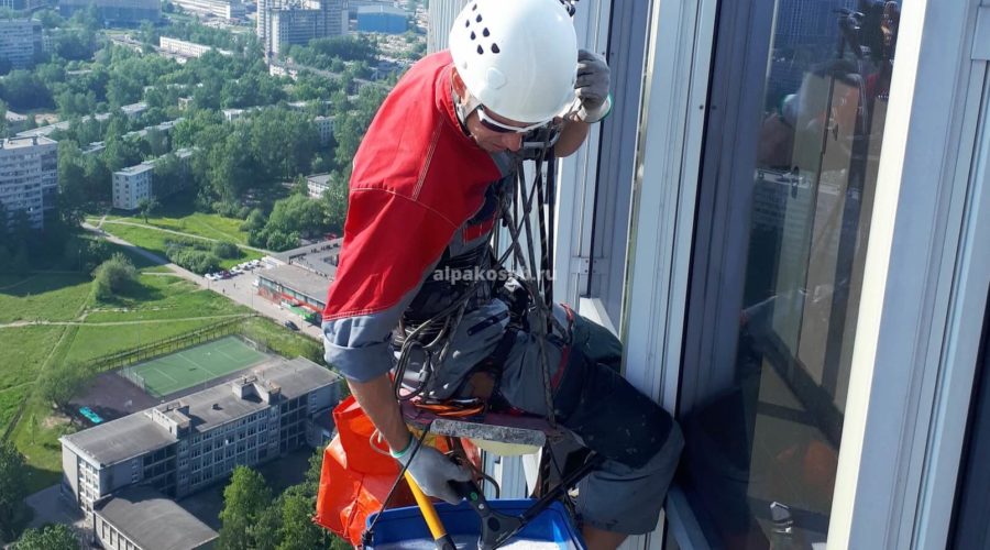 Промышленный альпинист на очень высоком здании моет окна