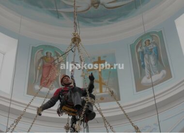 Промышленный альпинист на веревках в храме за работой