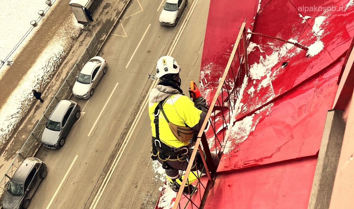 Красивая крыша с оконцами, с которой снимает наледь альпинист