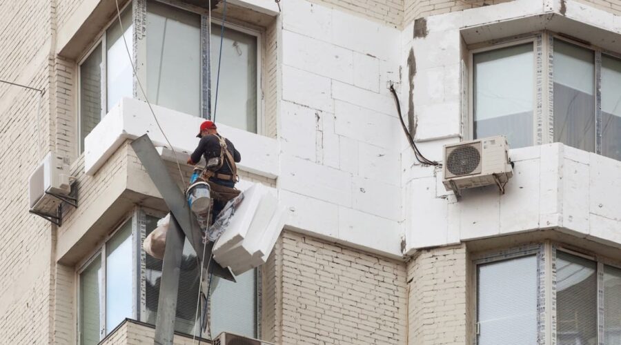Промышленный альпинист утепляет фасад здания