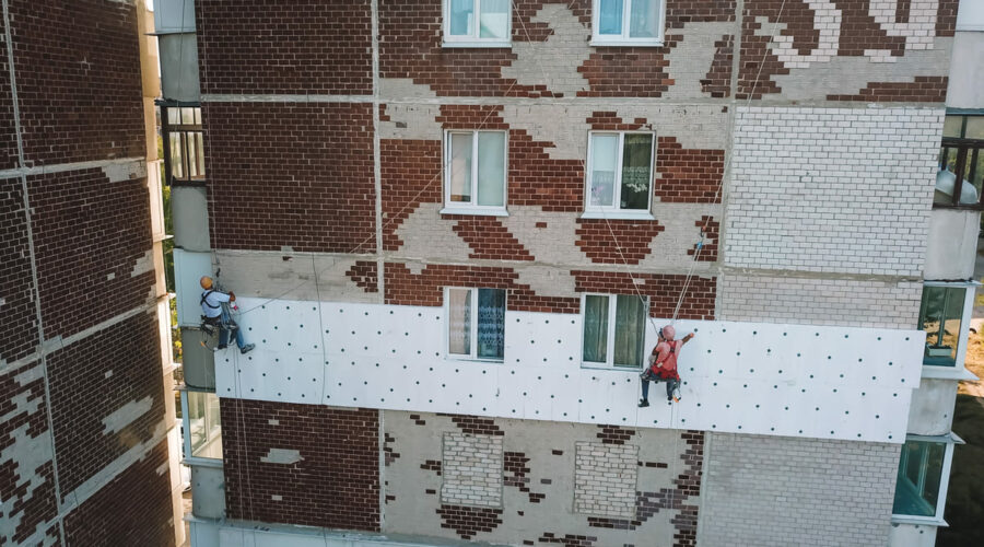 Два промышленных альпиниста утепляют фасад дома